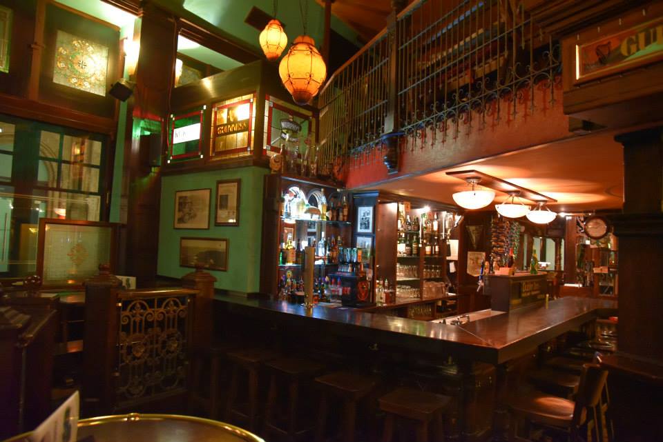 Main wooden bar with warm lamps inside Dublin Inn Hannover